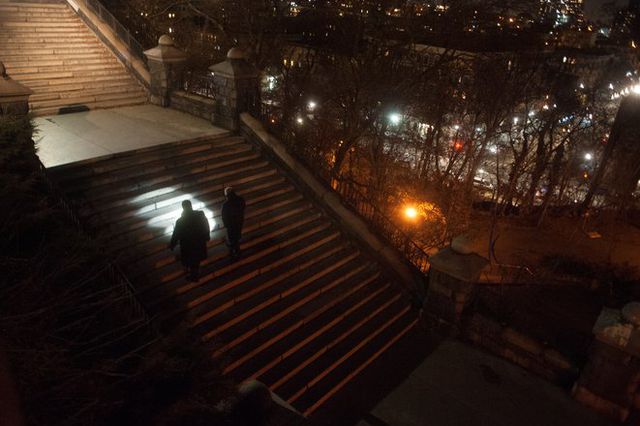 Two detectives walk up a set of stairs in Morningside Park at night.